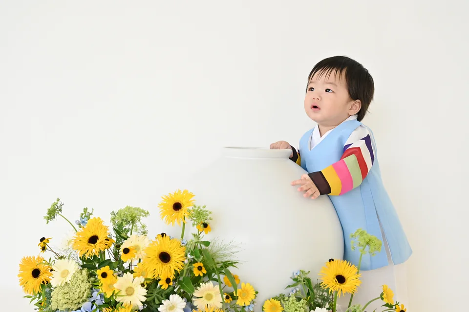 흰 달항아리 곁에 파란 한복을 입고 서 있는 도하