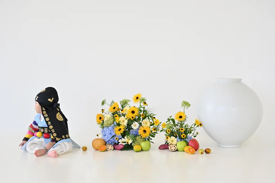 꽃꽂이와 달항아리 왼쪽에 한복을 입고 앉은 도하